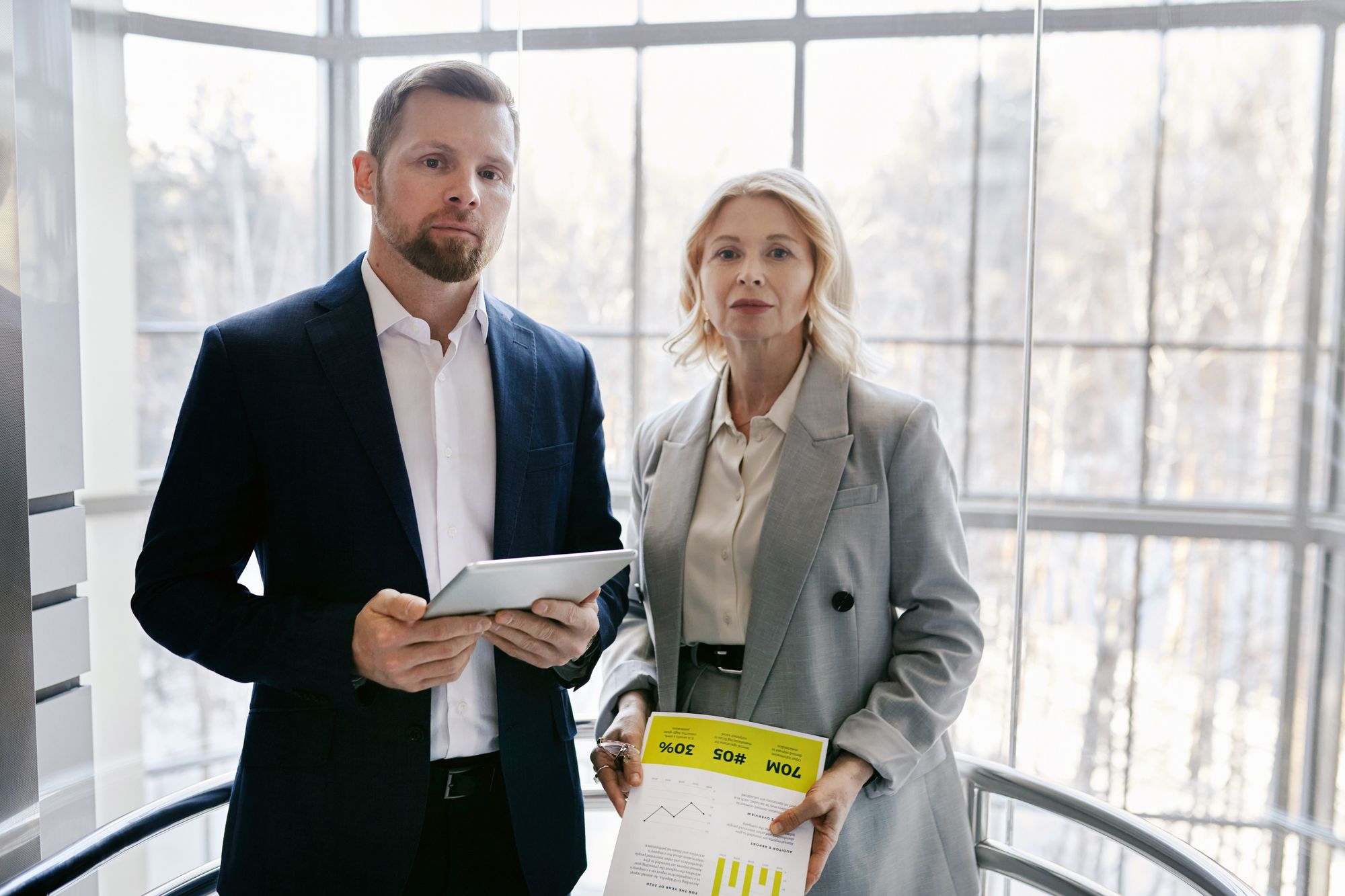 Two property professionals reviewing a report on a tablet inside a modern building