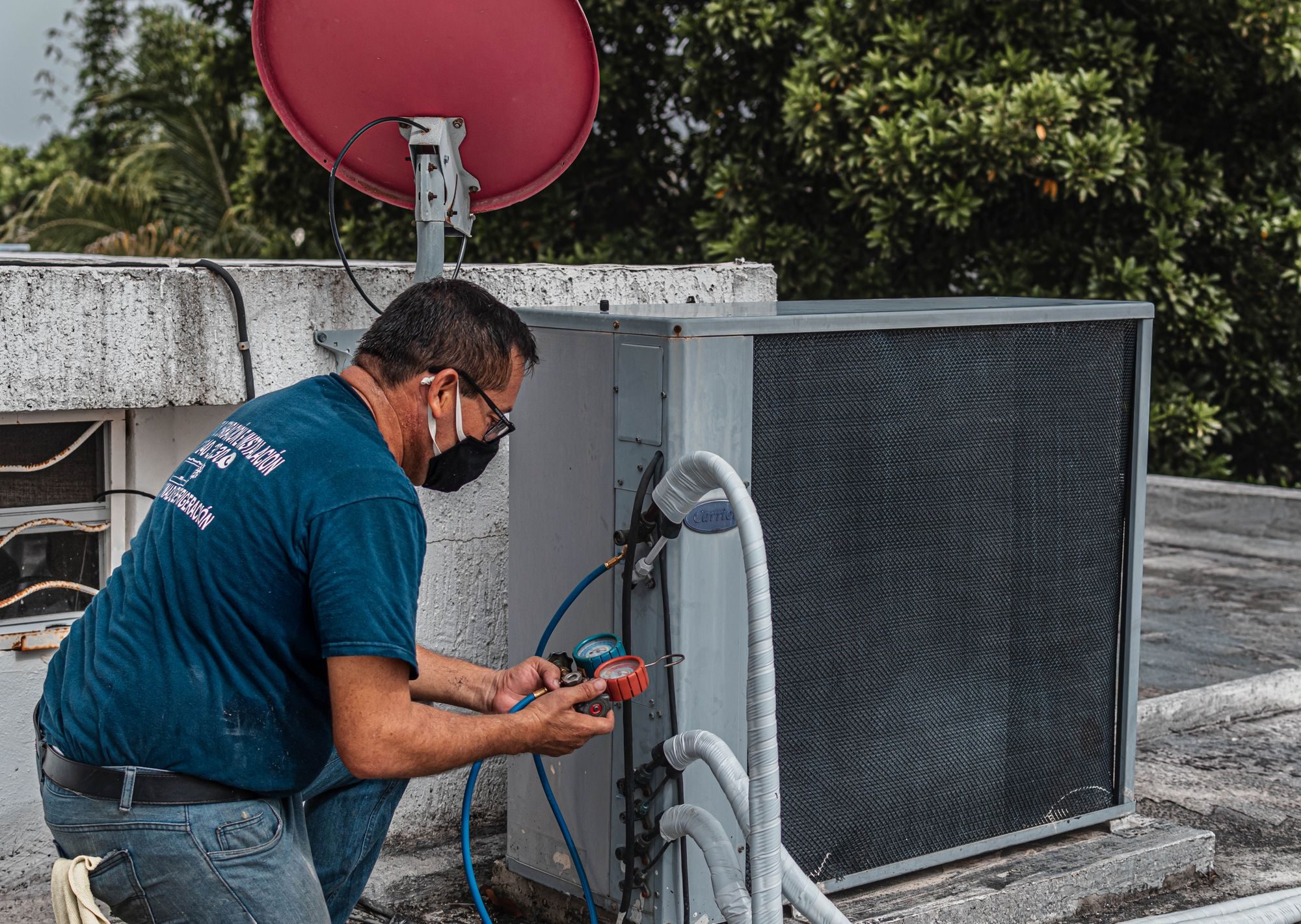 Air-conditioning technician checking a condenser unit with a manifold gauge