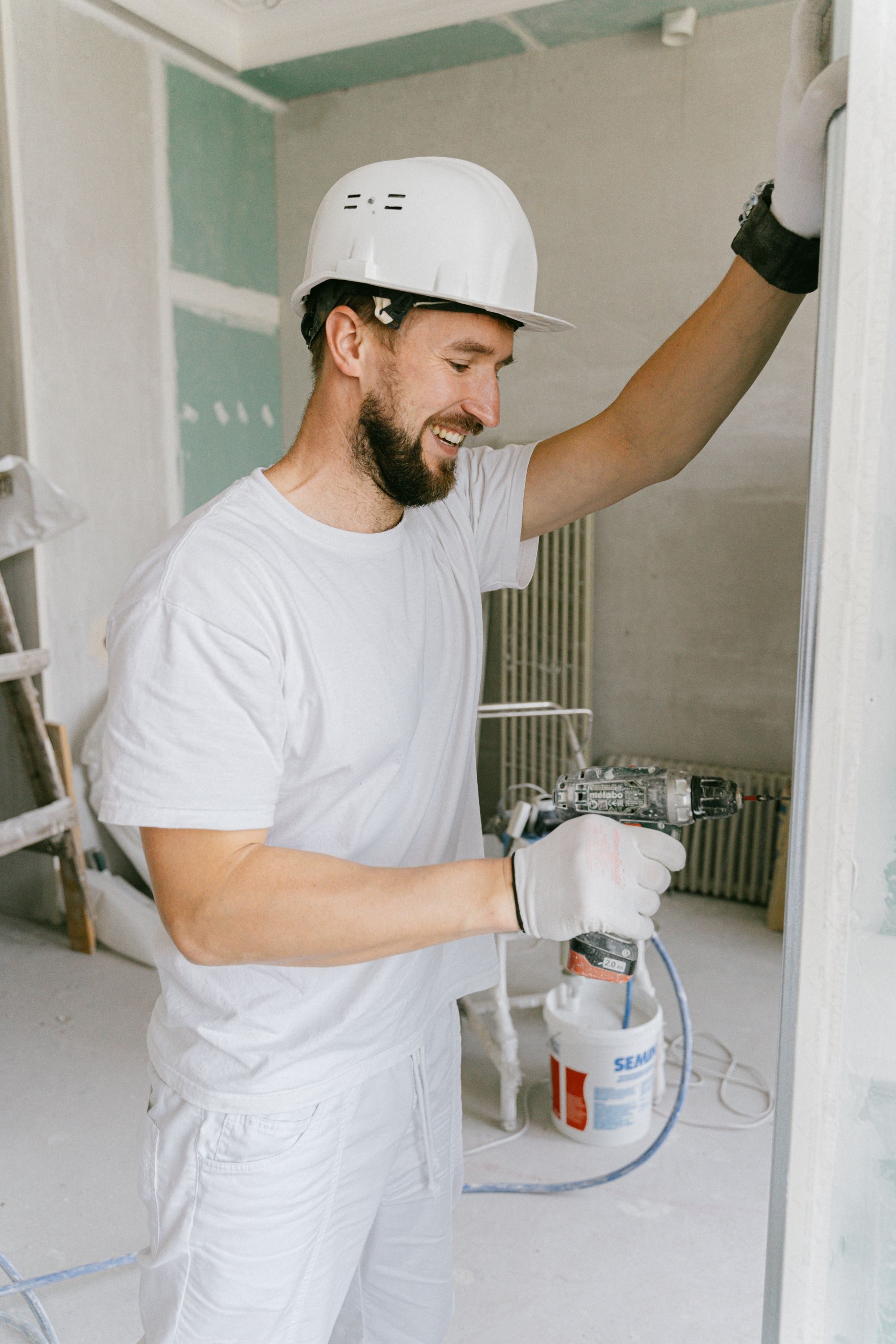 Renovation worker in white helmet drilling during interior building works