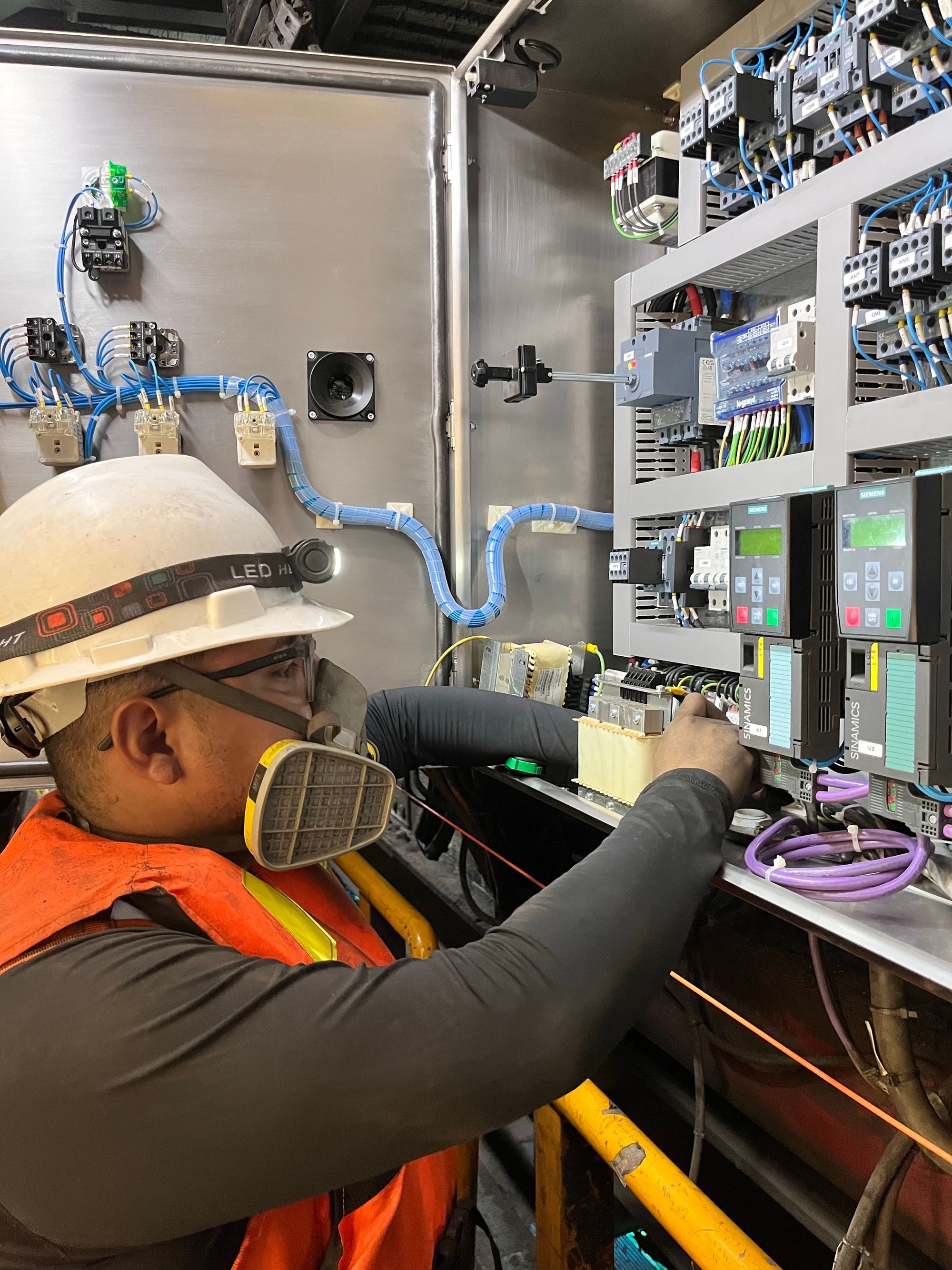 Electrician in safety helmet working on an industrial control panel
