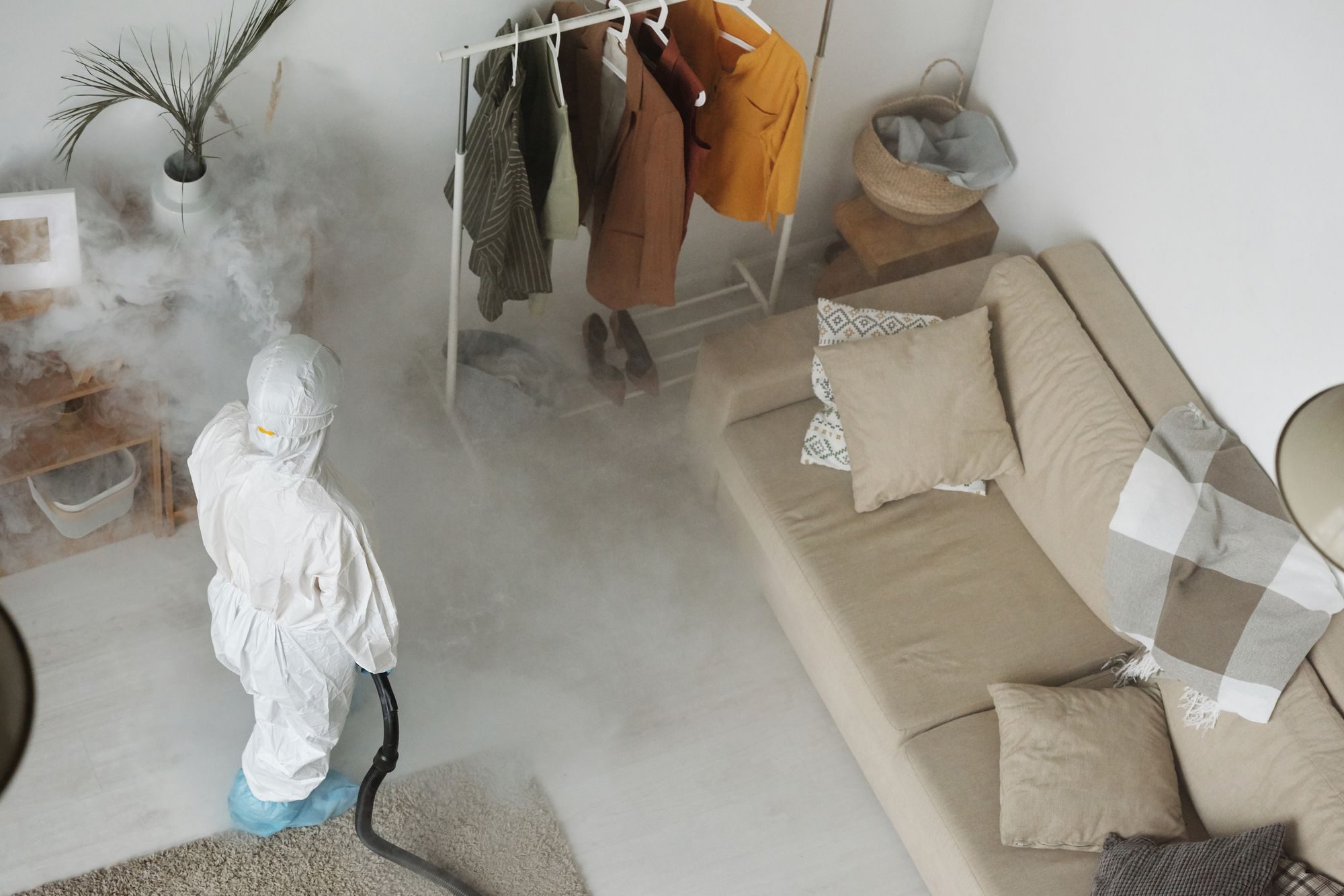 Pest control technician in protective suit misting a room