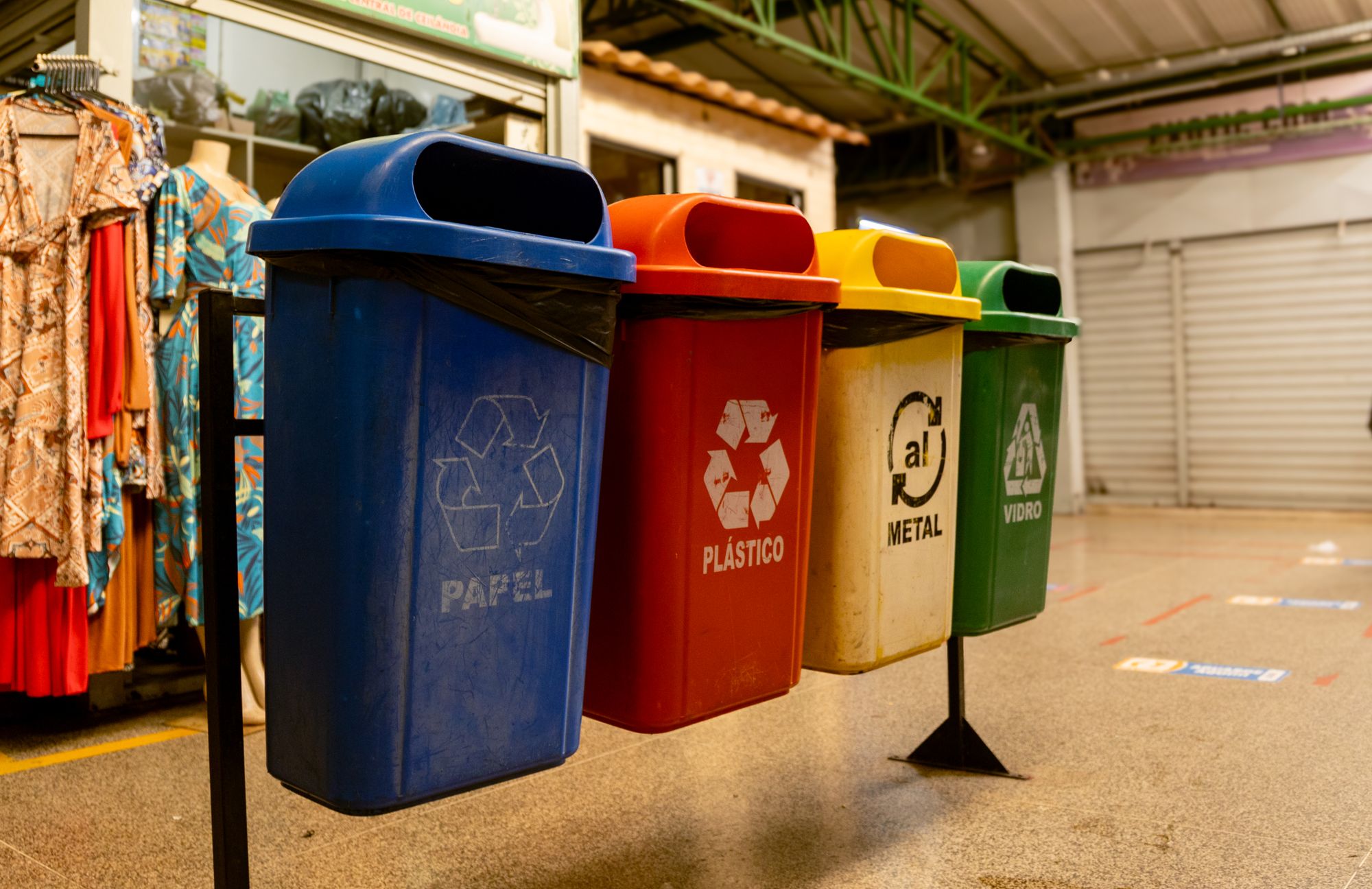 Row of colour-coded recycling bins for paper, plastic, metal and glass at a building