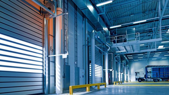 Interior of a modern logistics warehouse with roller-shutter loading bays and a parked truck