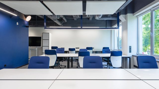 Bright open-plan office with white desks, blue chairs and large windows