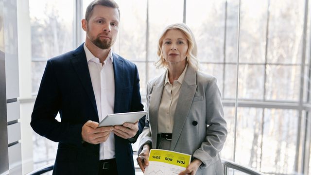 Two property professionals reviewing a report on a tablet inside a modern building