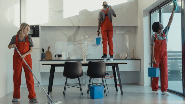 Uniformed cleaning crew mopping and wiping down a modern interior