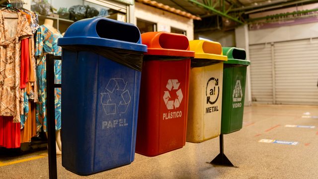 Row of colour-coded recycling bins for paper, plastic, metal and glass at a building